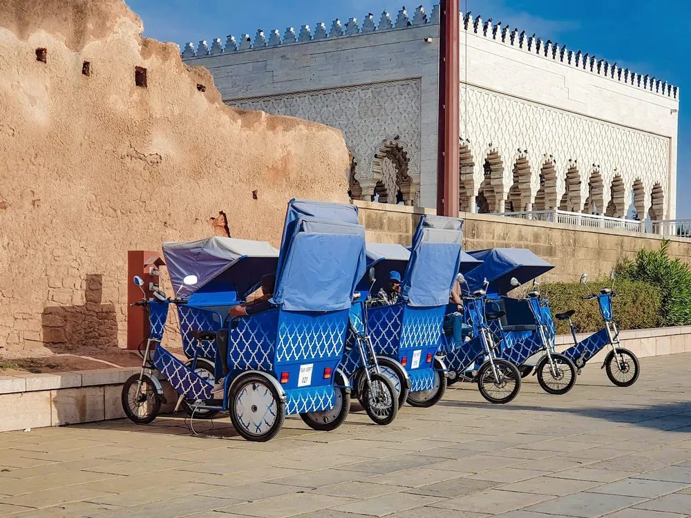 Blue tuk-tuks parked by the Mausoleum of Mohammed V