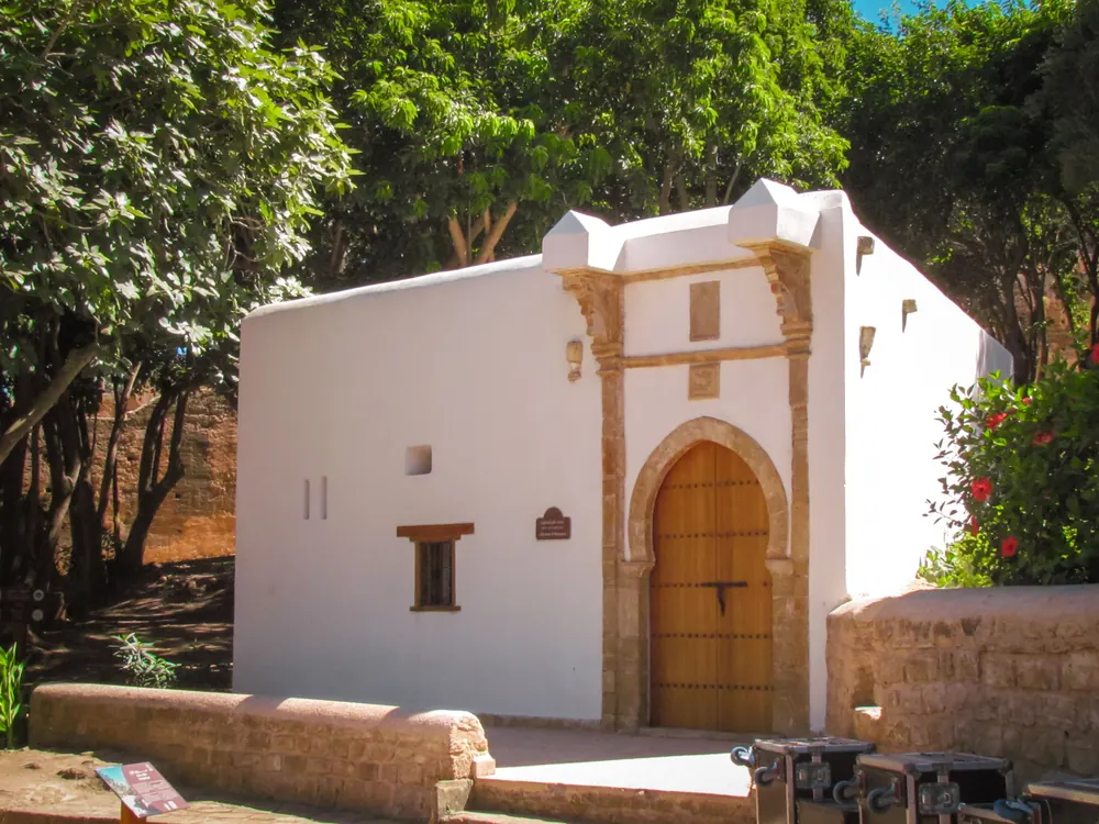 A white house with a carved doorway among the trees